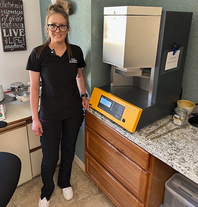Nicole standing next to sintering oven, creating dental crowns and bridges